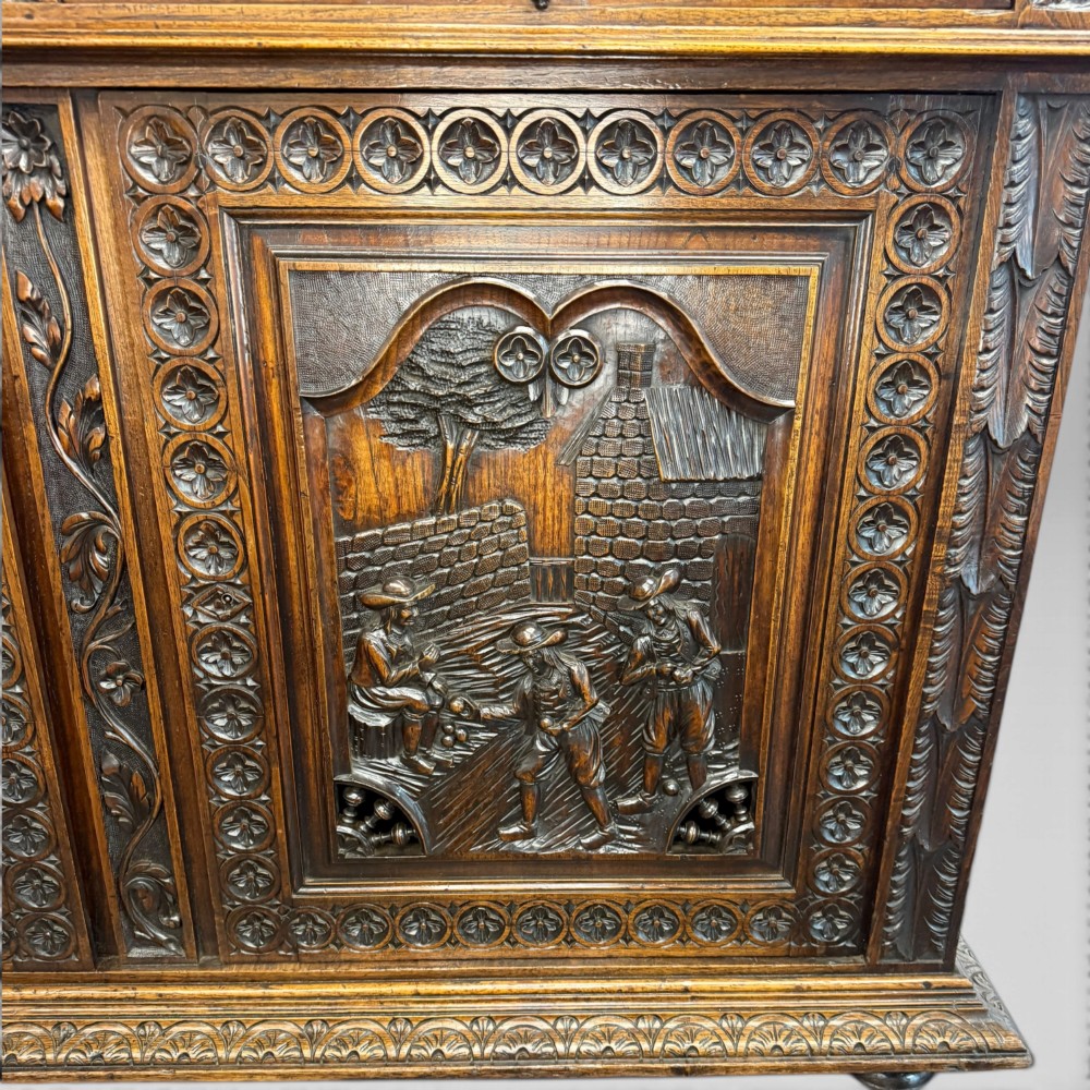 A mid-nineteenth-century dark oak French Breton buffet cabinet with detailed folk carvings, relief panels, ship wheel motifs, and carved human figure supports. View XI