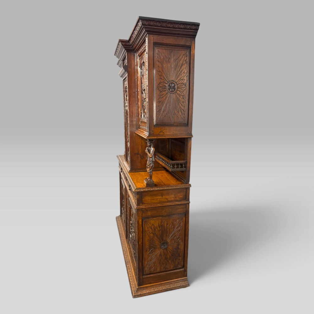 A mid-nineteenth-century dark oak French Breton buffet cabinet with detailed folk carvings, relief panels, ship wheel motifs, and carved human figure supports. View XII