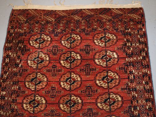 fig 1. An antique late 19th-century Tekke Turkmen wool rug featuring rows of octagonal gul medallions on a deep red ground with geometric borders.