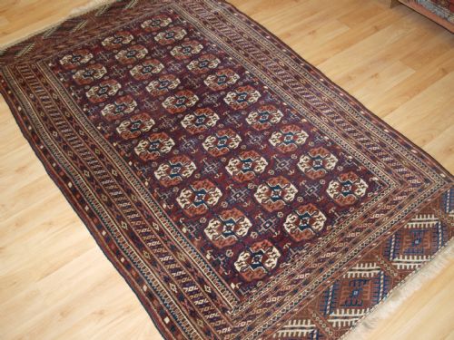 fig 1. An antique Tekke Turkmen wool rug featuring repeating geometric gul motifs on a deep red ground with multi-layered patterned borders.