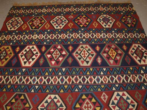 fig 1. A large flat-woven antique Caucasian Shirvan kilim rug featuring horizontal bands of geometric diamond motifs in red, navy blue, green, and yellow.