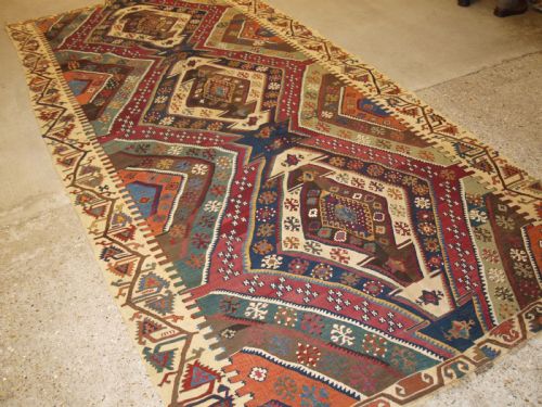 fig 1. A late 19th-century handwoven Turkish Malatya kilim rug featuring complex geometric diamond medallions in terracotta red, navy blue, green, and cream wool.