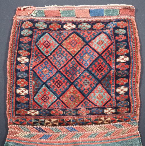 fig 1. An antique Kurdish Jaf tribal bag featuring a hand-knotted diamond geometric pattern on the front and a striped plain weave backing in red, blue, and teal shades.