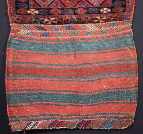 fig 2. An antique Kurdish Jaf tribal bag featuring a hand-knotted diamond geometric pattern on the front and a striped plain weave backing in red, blue, and teal shades.