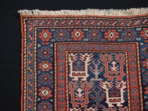 fig 1. A square antique woven wool Shahsavan Soumak textile panel displaying geometric dragon and bird motifs on a dark navy background framed by red floral borders.