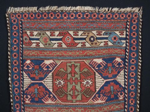 fig 1. A square antique Shahsevan Soumak woven wool panel featuring central geometric octagonal medallions flanked by bird and dragon motifs in shades of terracotta red, blue, and ivory.