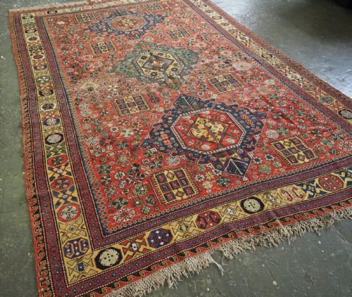 fig 1. An antique Caucasian flatweave Soumak rug featuring three large geometric medallions on a red field framed by a patterned yellow border.