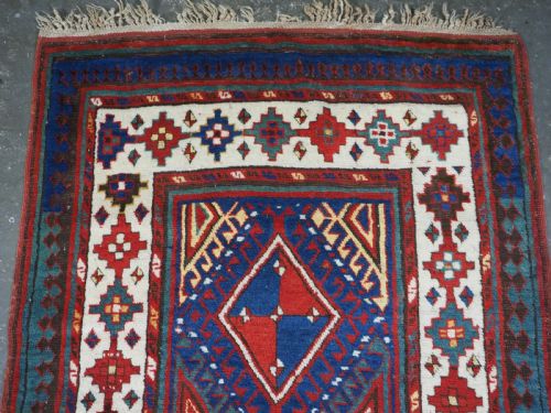 fig 1. An antique Caucasian Moghan Kazak wool runner rug with repeating diamond hooked medallions on a deep blue field and geometric borders.