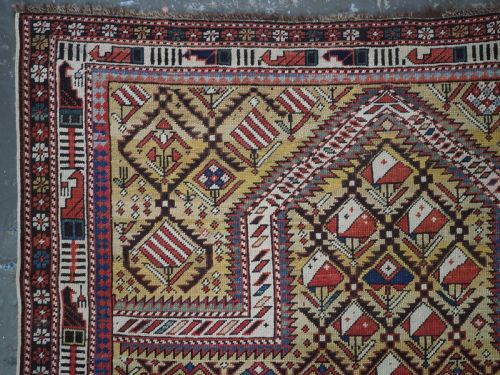 fig 1. A hand-knotted Caucasian Marasali prayer rug featuring a yellow ground with a prominent pointed mihrab arch, diamond lattice patterns, and geometric borders in red, blue, and brown.
