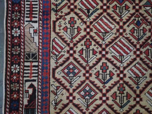fig 2. A hand-knotted Caucasian Marasali prayer rug featuring a yellow ground with a prominent pointed mihrab arch, diamond lattice patterns, and geometric borders in red, blue, and brown.
