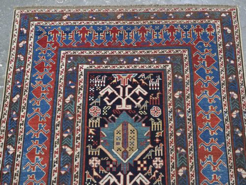 fig 1. An antique late nineteenth-century Caucasian Kuba runner featuring geometric medallions and stylised animal motifs in navy blue, red, and cream wool.