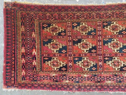 fig 1. A small rectangular antique Tekke Turkmen mafrash wool panel featuring a repeating grid of geometric aina gul motifs in deep red, dark blue, and cream.