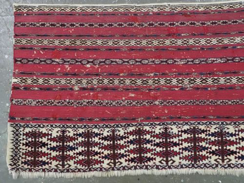 fig 1. An antique Tekke Turkmen Ak chuval face displaying red and dark blue horizontal bands above a patterned ivory geometric lower panel.