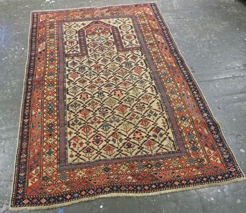 fig 1. An antique Caucasian Shirvan prayer rug featuring an ivory ground decorated with a geometric floral lattice pattern and a arched mihrab.