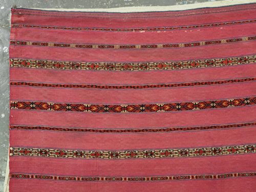 fig 1. An antique rectangular Tekke Turkmen Kizil chuval woven textile with detailed horizontal geometric bands across a magenta red wool field.