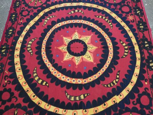fig 2. A rectangular crimson Uzbek suzani textile featuring heavy silk embroidery with a central star motif inside concentric circular borders.