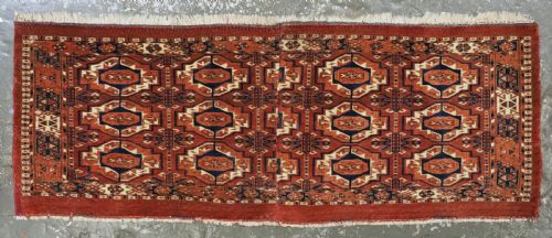 fig 1. An antique Tekke Turkmen wool torba fragment featuring fifteen repeating octagonal geometric guls in terracotta red, cream, and navy blue.