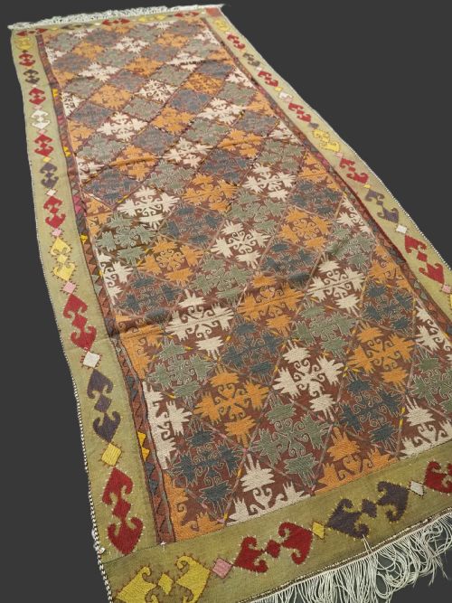 fig 1. A long rectangular antique Uzbek handwoven wool suzani runner rug with a diamond lattice pattern and geometric border motifs in earth tones.