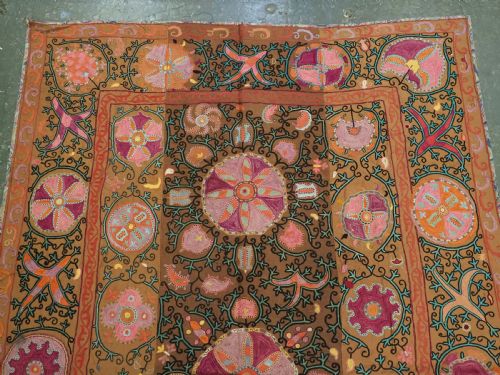 fig 1. An antique Uzbek Shahrisabz region suzani textile with pink and orange silk embroidered floral medallions on a brown cotton field.