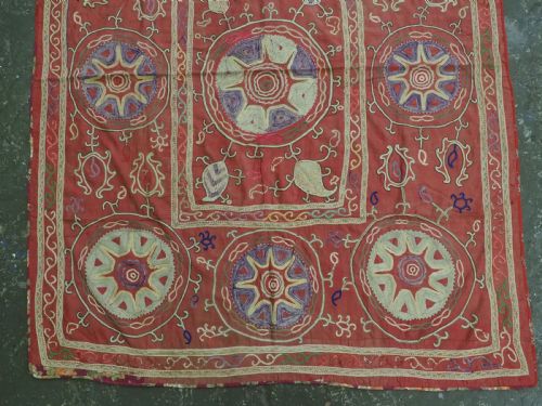 fig 2. A rectangular red cotton embroidered suzani featuring geometric starburst medallions and floral scrolling borders worked in multi-coloured silk thread.