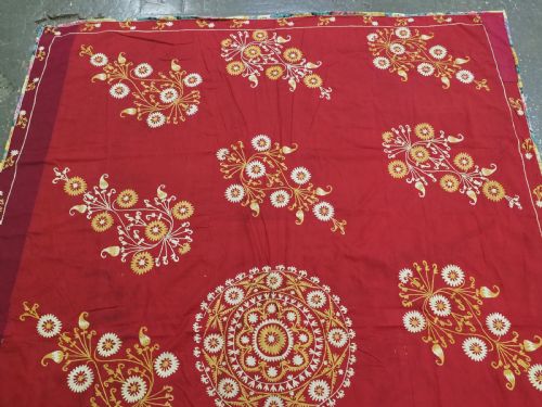 fig 1. A rectangular red adras silk and cotton textile featuring yellow and white silk thread embroidery with a central circular floral medallion, surrounding floral sprays, and a matching decorative border.