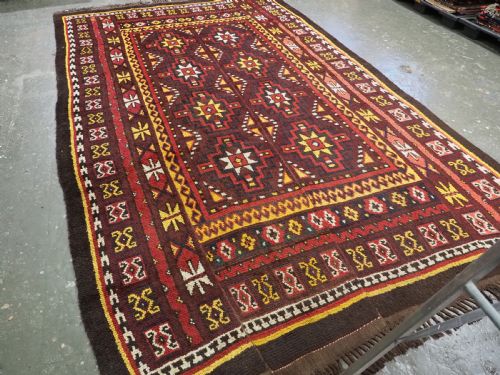 fig 1. An antique handwoven Uzbek Julkyrs rug with geometric star motifs constructed from four vertical wool strips stitched together in tones of brown, red, and yellow.