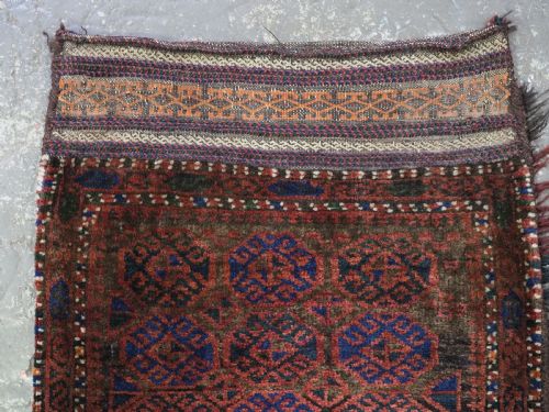 fig 1. An antique woven Baluch Balisht storage bag featuring dark red and navy blue geometric octagonal motifs with a flat-weave top border and fringed edges.