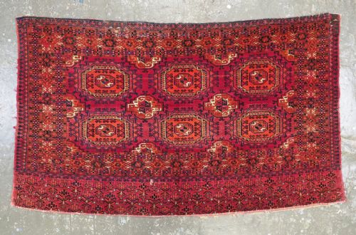 fig 1. An antique Tekke Turkmen chuval face textile featuring six octagonal turreted guls framed by geometric borders in deep red, navy, and cream wool.