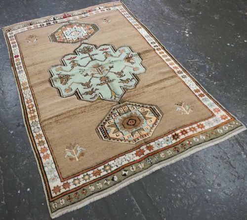 fig 1. An antique hand-knotted Turkish Konya Karapinar rug featuring a camel wool field and geometric medallions in turquoise and terracotta.