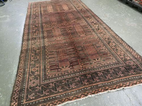 fig 1. A long, dark-toned hand-knotted wool rug displaying a repeating geometric pencil box motif within complex outer geometric borders.