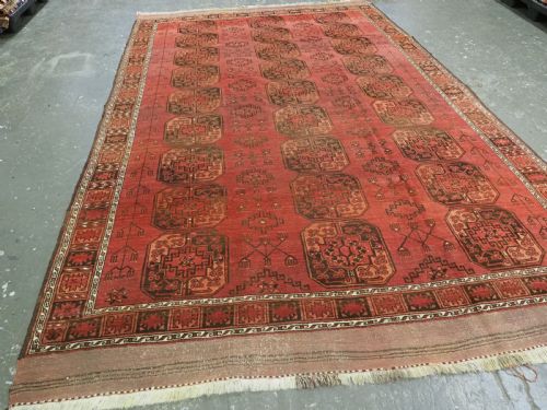 fig 1. An antique Ersari Turkmen carpet from circa 1890 featuring repeating octagonal guls across a deep terracotta red wool field with geometric borders.