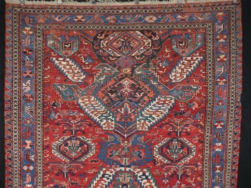 fig 1. An antique hand-woven Caucasian Soumak flatweave rug featuring a red ground with geometric dragon medallions and a patterned border.