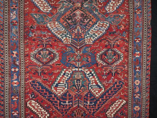 fig 2. An antique hand-woven Caucasian Soumak flatweave rug featuring a red ground with geometric dragon medallions and a patterned border.