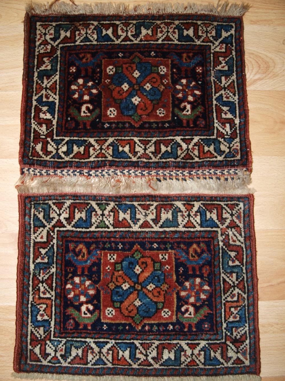 A pair of rectangular antique Persian tribal chanteh bag faces featuring geometric medallions and bird motifs in deep blue, red, and ivory wool.