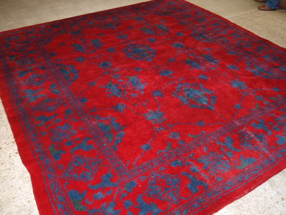 ANTIQUE IRISH DONEGAL CARPET IN TURKISH OUSHAK DESIGN, RED AND BLUE, SQUARE SHAPE, CIRCA 1900.