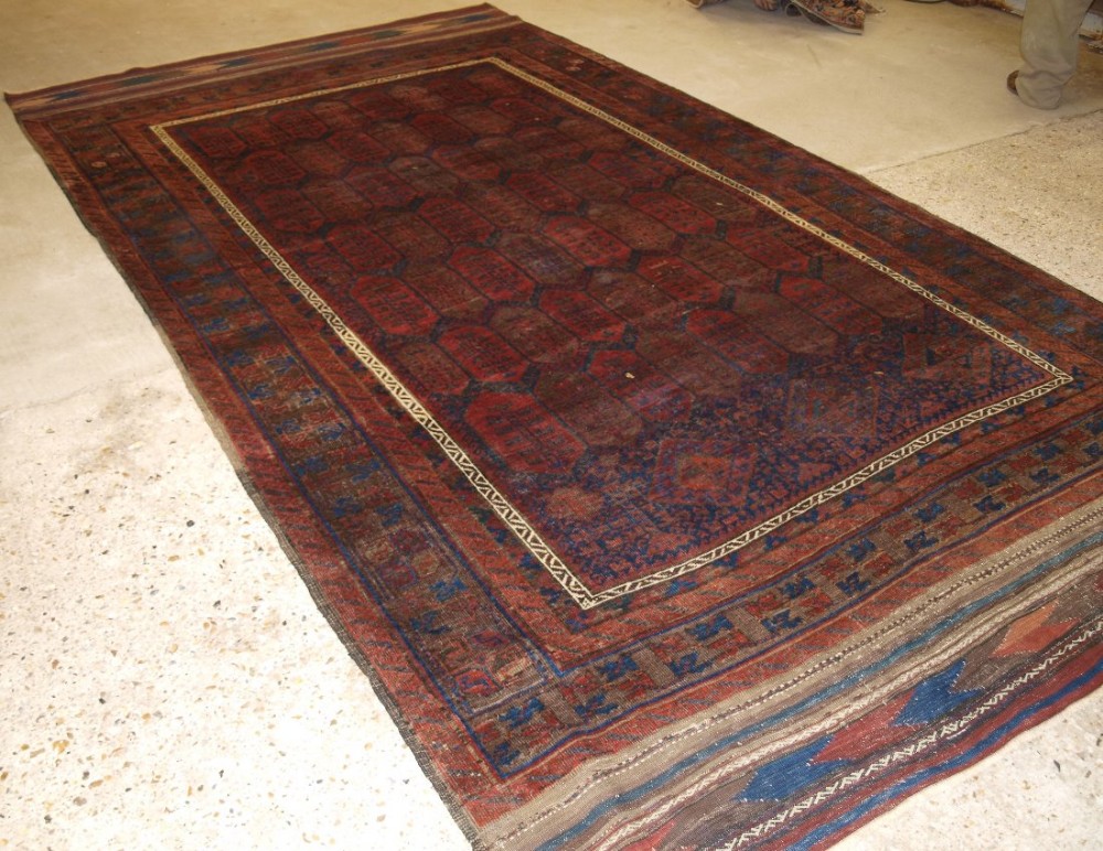 ANTIQUE WESTERN AFGHAN BALUCH CARPET, SHRUB DESIGN, LONG KILIM ENDS, CIRCA 1870.
