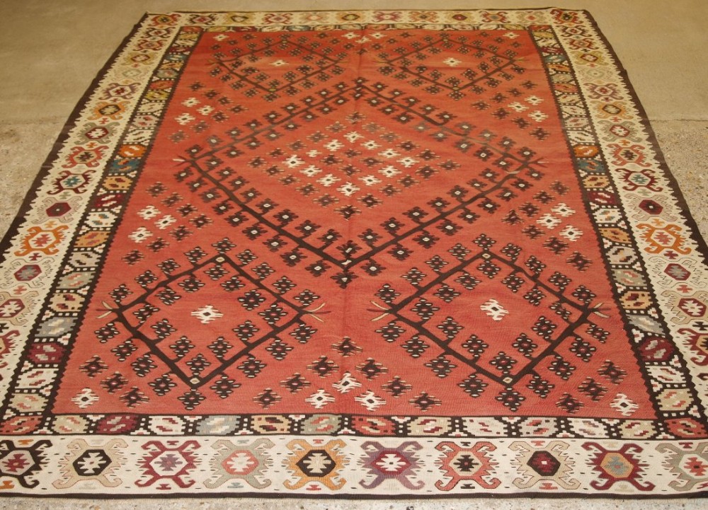 OLD TURKISH SARKOY KILIM RUG, TRADITIONAL DESIGN ON SOFT RED GROUND, CIRCA 1920.