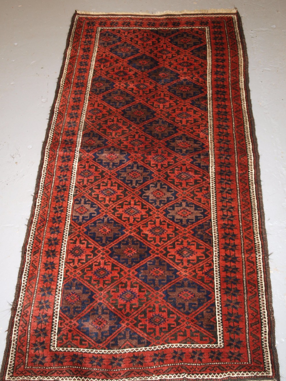 ANTIQUE BALUCH RUG WITH LATTICE DESIGN, STAR BORDER, CIRCA 1900.