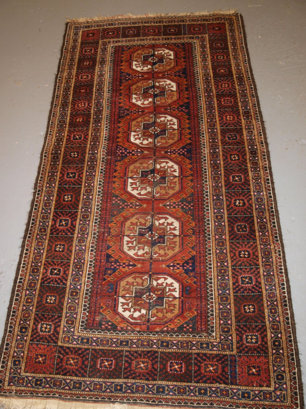 ANTIQUE BALUCH RUG BY THE MAHDAD KHANI TRIBE, LARGE TEKKE GULS, CIRCA 1900.
