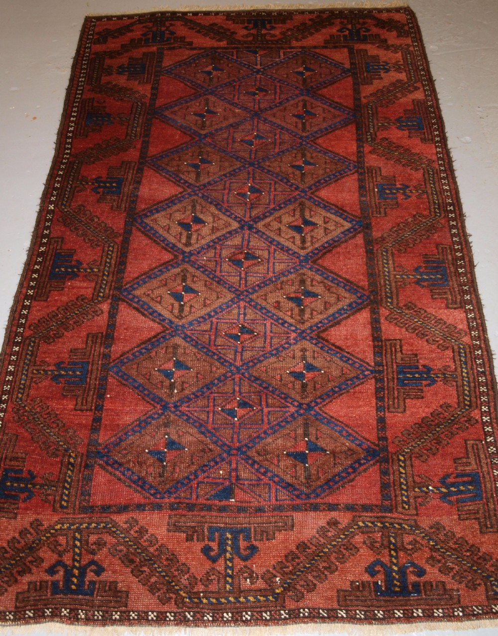 ANTIQUE AFGHAN RUG OF BALUCH LATTICE DESIGN, WARM COLOURS, CIRCA 1900/20.