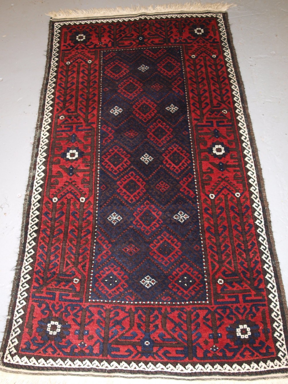 OLD AFGHAN BALUCH RUG WITH REPEAT DESIGN AND CLASSIC BALUCH BORDER, CIRCA 1920.