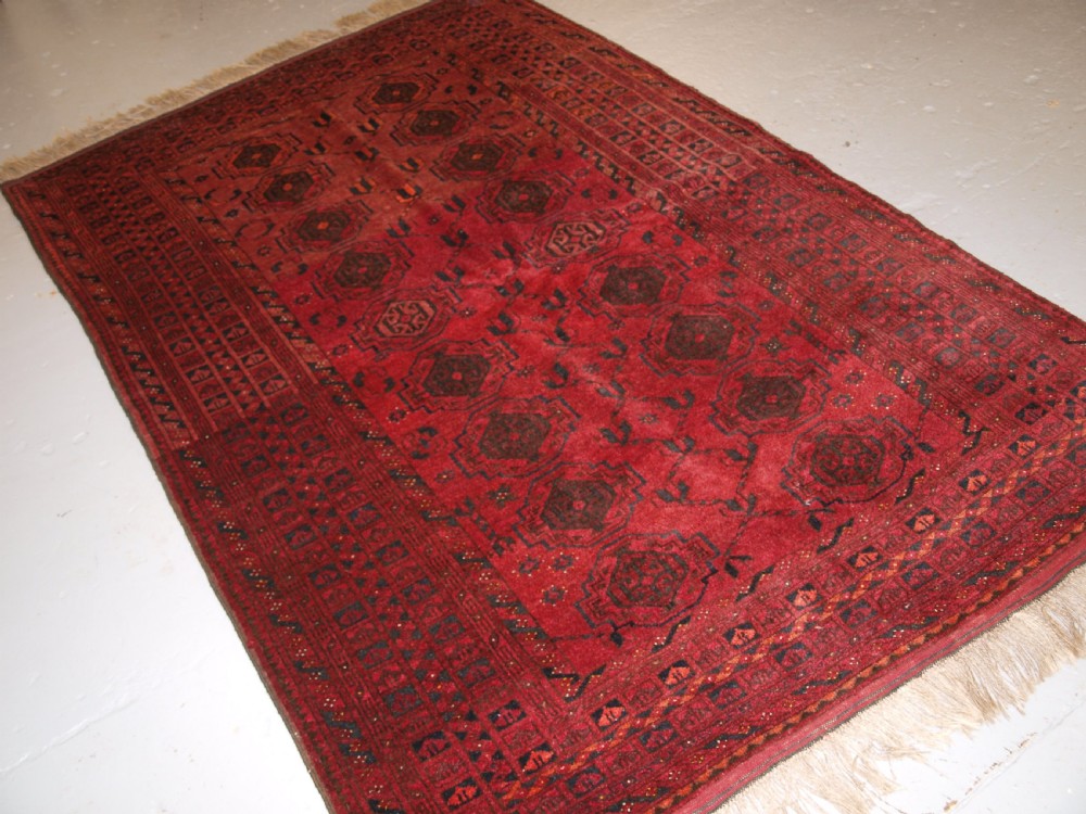OLD AFGHAN VILLAGE RUG WITH TURKMEN CHUVAL GUL DESIGN, PLUM RED COLOUR, CIRCA 1920.