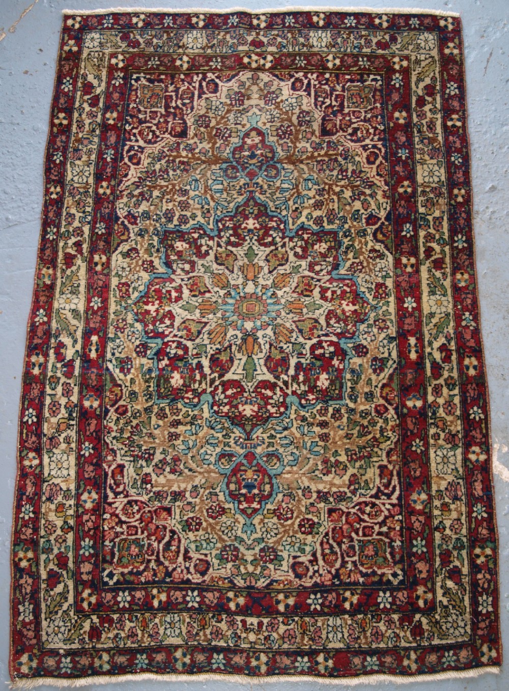 ANTIQUE PERSIAN KIRMAN RUG OF SMALL SIZE, FINE WEAVE AND PLEASING COLOUR, CIRCA 1900.
