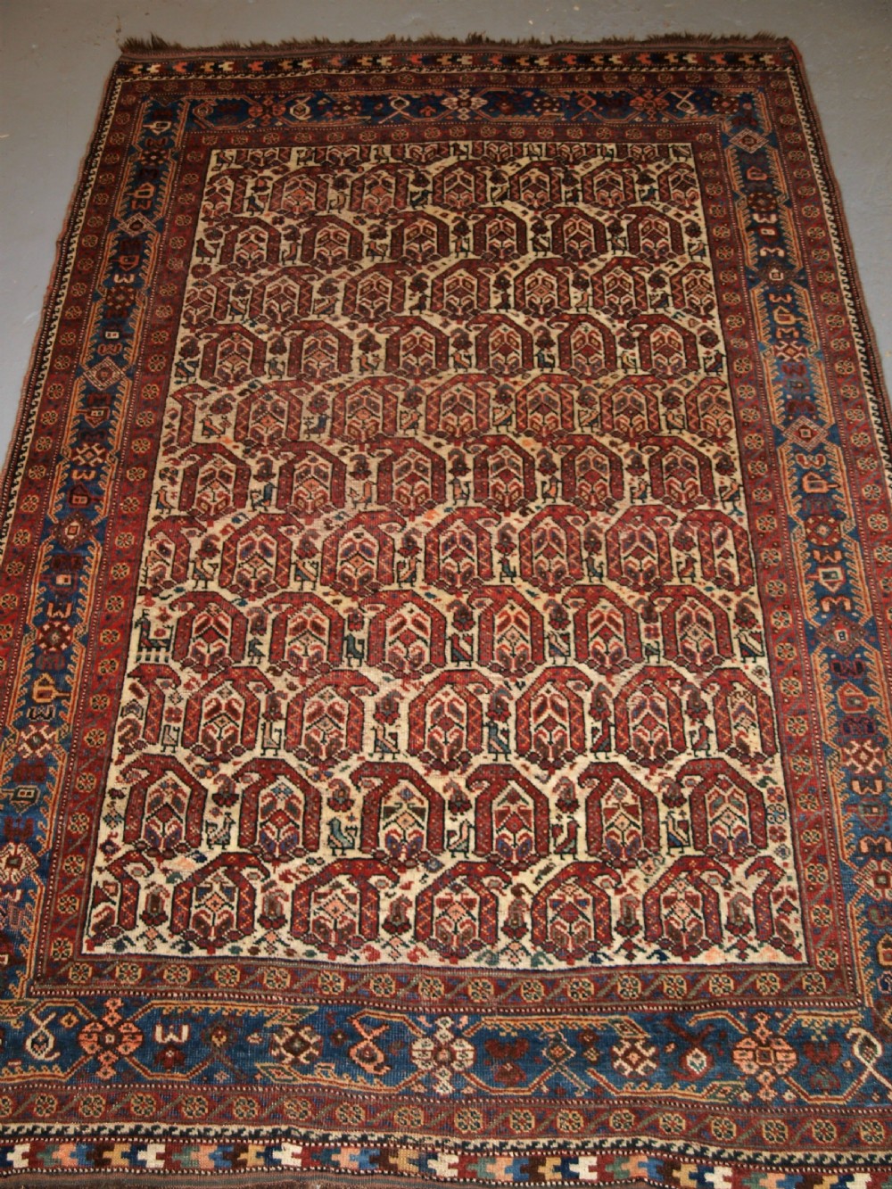 ANTIQUE RUG BY THE KHAMSEH TRIBE, ALL OVER BOTEH DESIGN ON AN IVORY FIELD, CIRCA 1900.