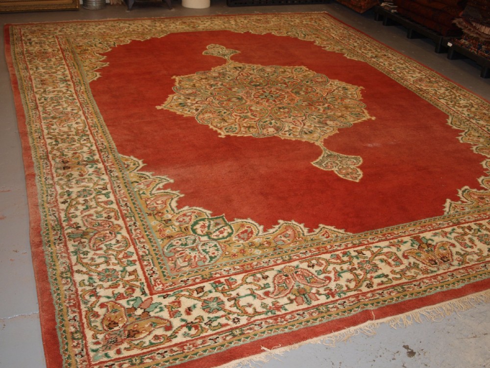 An antique Turkish Isparta wool carpet featuring a warm red field decorated with a central floral medallion and pastel borders.
