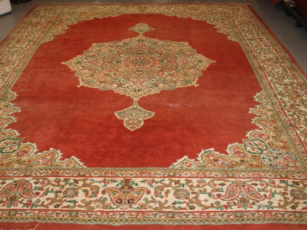 An antique Turkish Isparta wool carpet featuring a warm red field decorated with a central floral medallion and pastel borders. View II