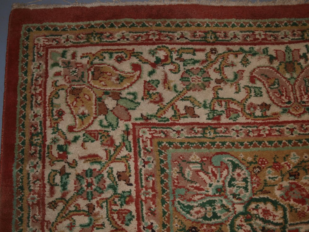 An antique Turkish Isparta wool carpet featuring a warm red field decorated with a central floral medallion and pastel borders. View III
