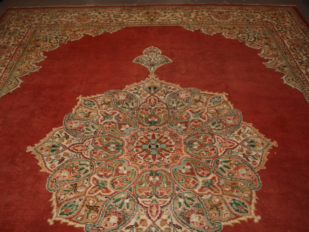An antique Turkish Isparta wool carpet featuring a warm red field decorated with a central floral medallion and pastel borders. View IV