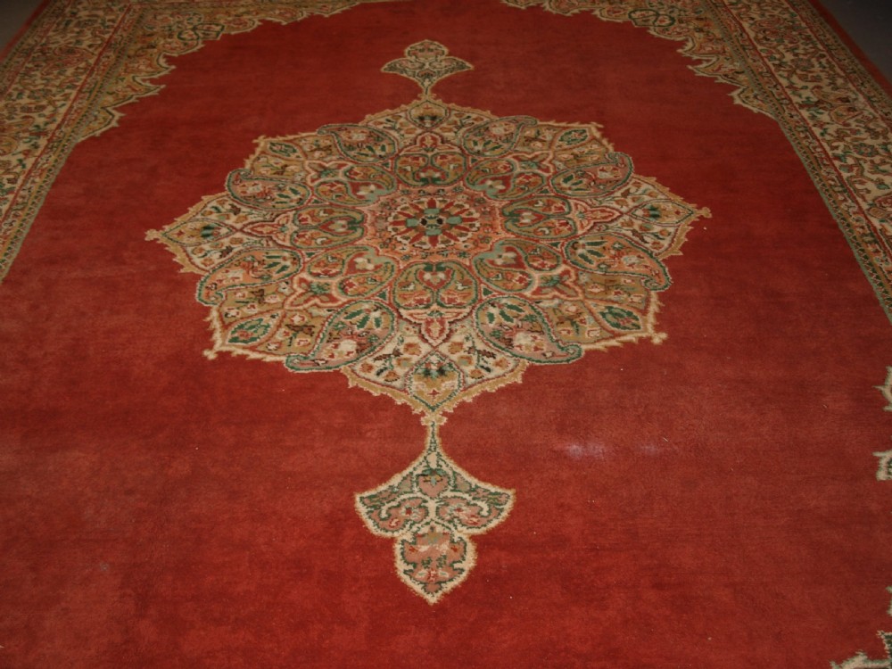 An antique Turkish Isparta wool carpet featuring a warm red field decorated with a central floral medallion and pastel borders. View V