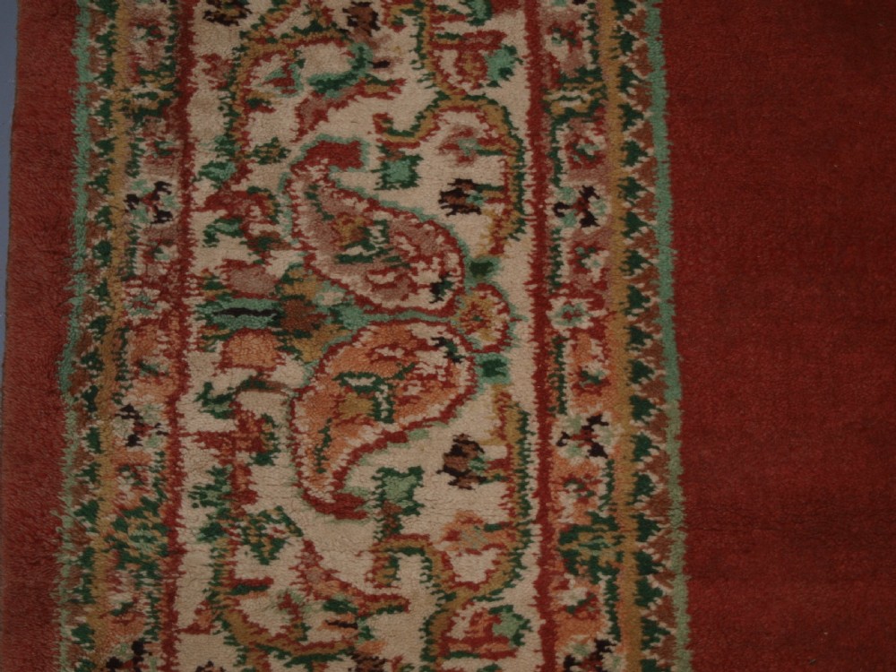 An antique Turkish Isparta wool carpet featuring a warm red field decorated with a central floral medallion and pastel borders. View VI